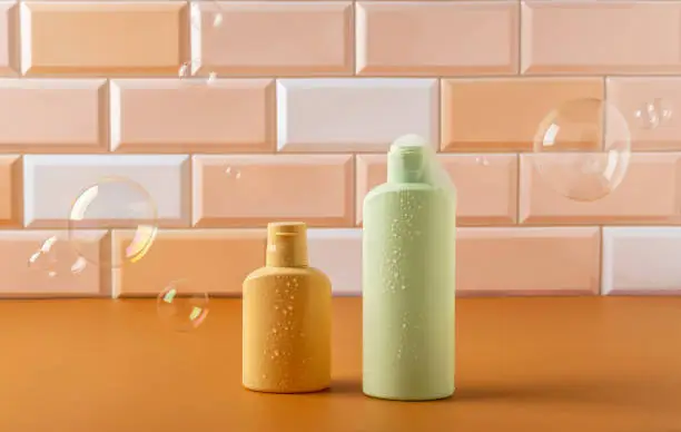 Cosmetic products for hair or skin care standing in the bathroom. Shampoo or shower gel with soapbubble. Space for text.