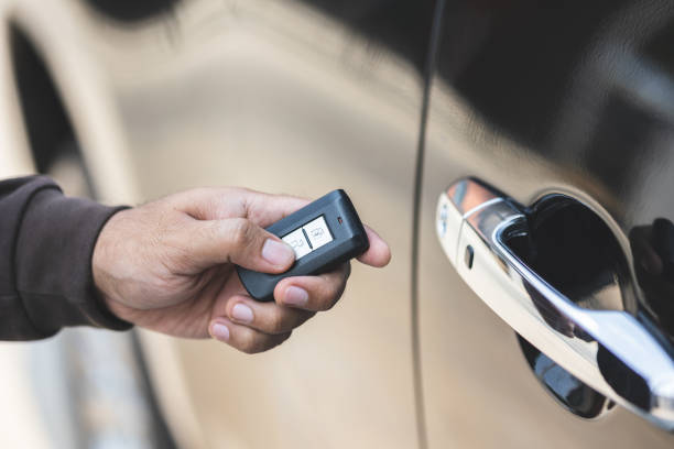 nahaufnahme männliche hand halten autoschlüssel. mann entsperren autotür durch entfernte taste drücken in der nähe von auto-tür. - car door push button lock car stock-fotos und bilder