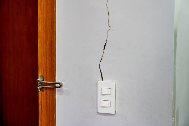 Close up photo of cracked wall texture near the light switch stock photo