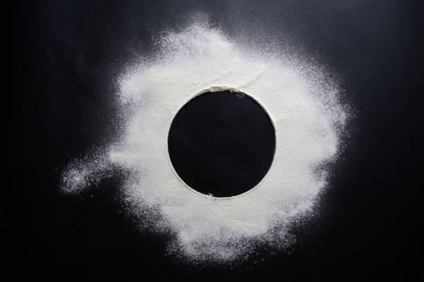 istock Abstract background. Sprinkled wheat flour circle, round spot on black. Top view on blackboard. Baking concept, cooking dough or pastry. 1310753289