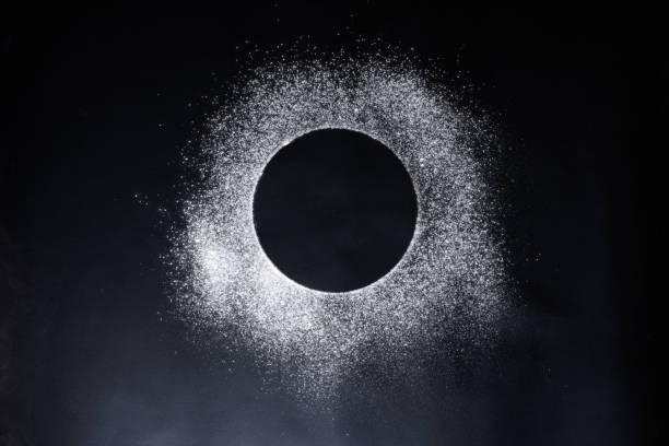 Abstract background. Sprinkled wheat flour circle, round spot on black. Top view on blackboard. Baking concept, cooking dough or pastry.