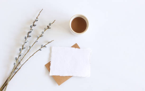 istock Spring still life.Easter composition with goat willow, pussy willow or great sallow, blank paper sheet mockup, a cup with coffee on white wooden table background.Top view. Place for your text. 1310754835