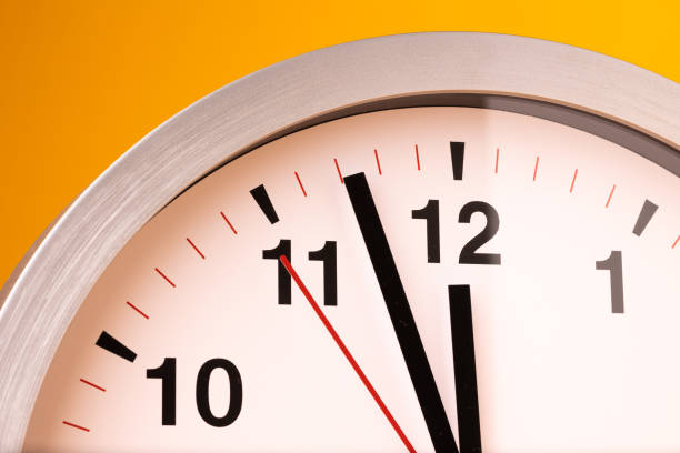istock Large white alarm clock, black numbers, set the time placed on a table. Clock on isolated yellow background. 1310754895