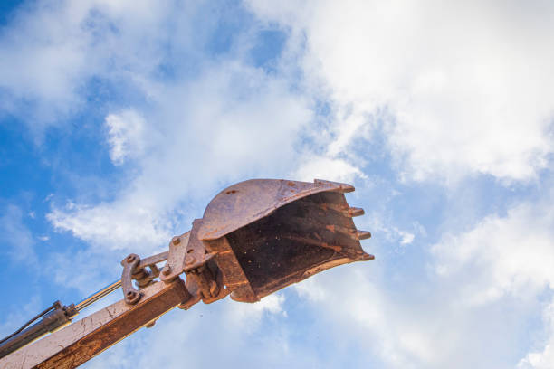 detail of excavator bucket filled with soil under blue sky