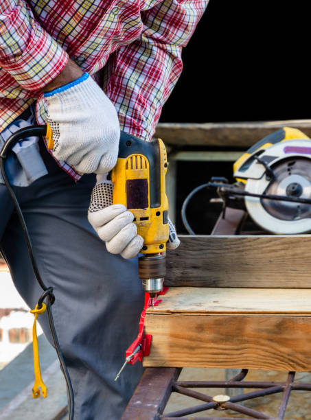 Man drilling a hole in the wooden board Male carpenter drills a hole into a  wooden plank with an electrical corded drill for screwed butt joint. Tools and equipment for woodworking concept. power tool photos stock pictures, royalty-free photos & images