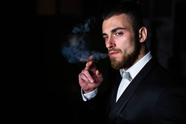 istock A handsome man in a suit blowing out cigar smoke 1310756990