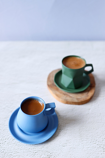 Istanbul, Turkey-April 3, 2021: Sparkling Turkish coffee in a blue and green ceramic cup on a light gray concrete floor. Flat lay, Still life, Full Frame, Sunlight. Shot with Canon EOS R5.