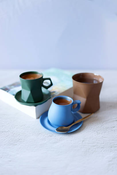 Sparkling Turkish coffee in a blue and green ceramic cup on a light gray concrete floor, Front view