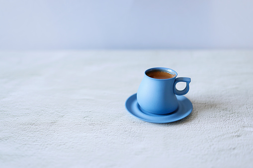 Istanbul, Turkey-April 3, 2021: Sparkling Turkish coffee in a blue ceramic cup on a light gray concrete floor. Still life, Full Frame, Sunlight. Shot with Canon EOS R5.