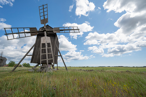 Low angle view of a traditional old weathered windmill in Oland, Öland, with clouds on a blue sky