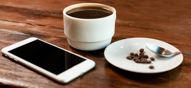 istock Cup of coffee with coffee beans and device on wooden table 1310760833