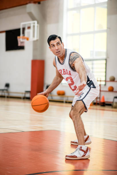 istock Dark-haired athletic man playing basket-ball in the gym 1310761838