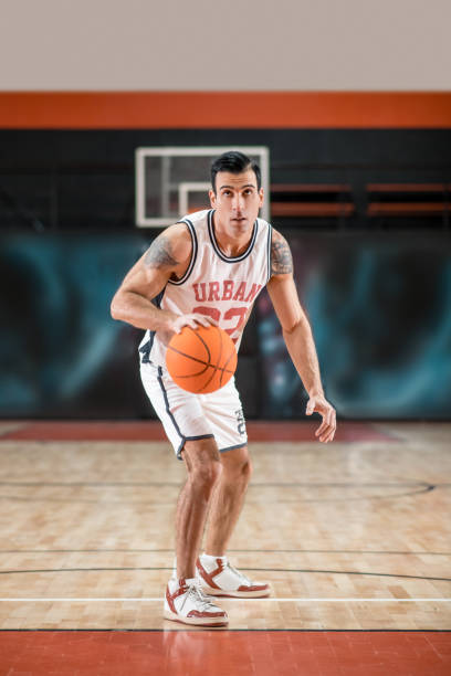 istock Dark-haired athletic man playing basket-ball in the gym 1310761839