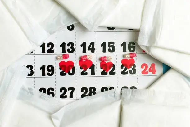 Photo of Menstruation cycle concept. Menstruation calendar with sanitary pads, contraceptive pills.
