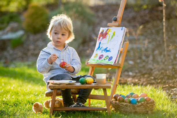 dolce bambino bambino, dipingendo uova in giardino con piccoli pulcini che corrono intorno a lui - baby chicken young bird easter bird foto e immagini stock