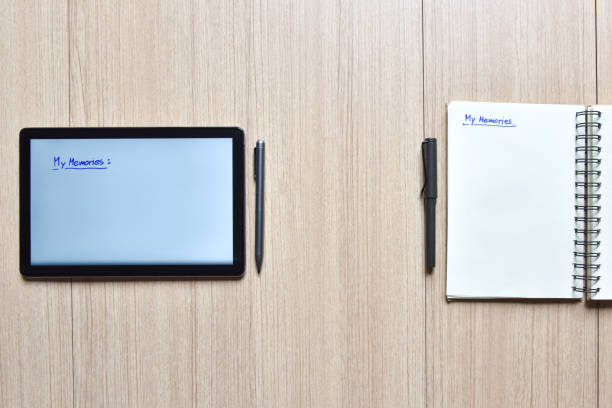 istock a tablet and notebook with pens on wood table,old and new style of technology to note and take a memo for note or lists concept 1310771124