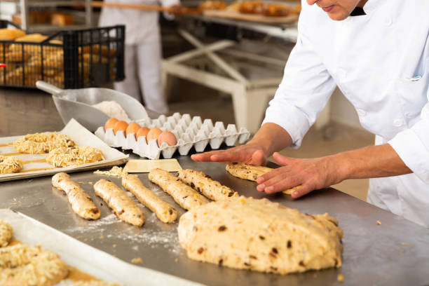 istock Male baker working with dough shaping baguettes 1310774454