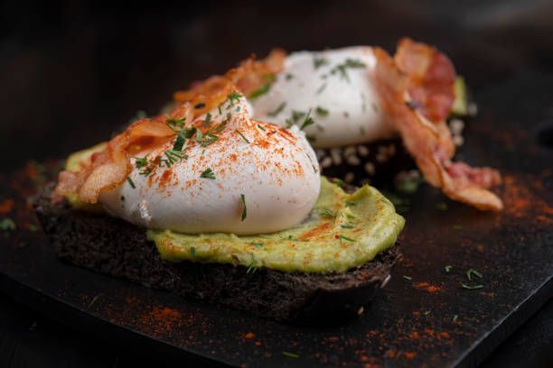 istock Poached eggs with bacon on toasts. Laid out on black slate. 1310775337