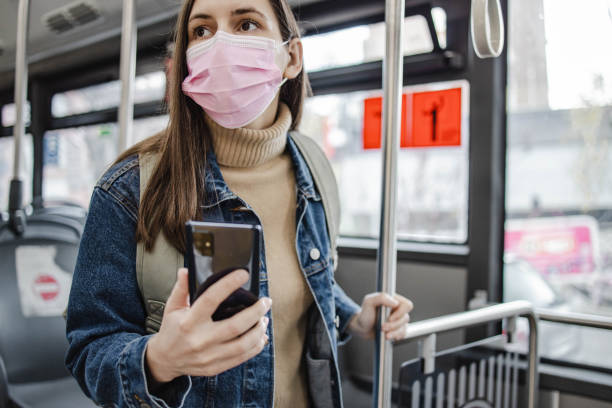 istock Woman with a protective face mask in a bus, using smart phone 1310775514