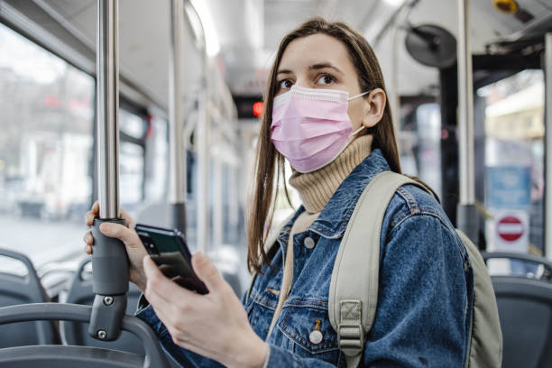 istock Woman with a protective face mask in a bus, using smart phone 1310775536