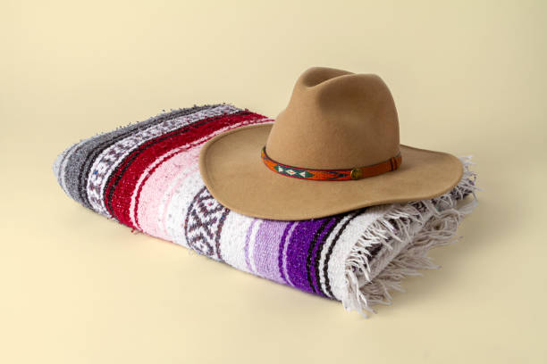 Cowboy hat on a folded Southwestern blanket with a beige background