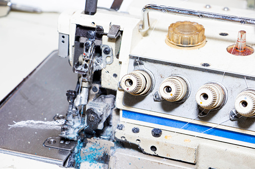 Four-thread industrial sewing machine overlock. An overlock is a type of stitch that sews along the edge of one or two pieces of fabric for edging.