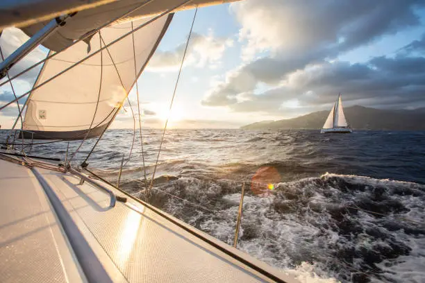 Two sailing yachts are sailing towards the rising sun. Aegean Sea.