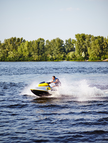 Strong man jumps on the jetski above the water. Man speeding on jet ski on lake during summer vacation