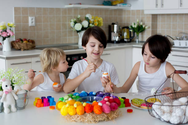 istock Three children, sibling brothers, painting easter eggs for decoration 1310788157