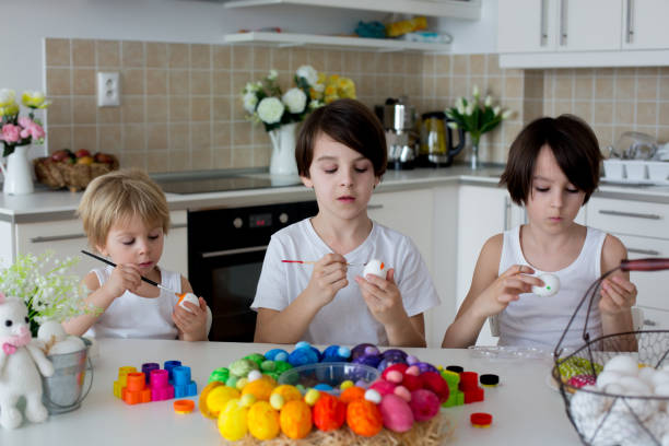 istock Three children, sibling brothers, painting easter eggs for decoration 1310788192