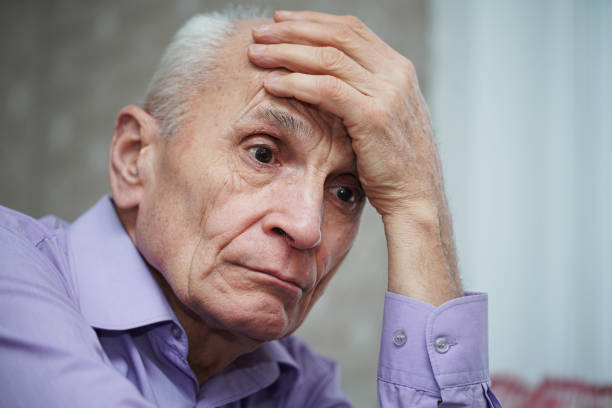 istock Sorrowful elderly hoary man holds head with hand side close view. 1310788588