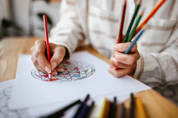 Mature woman is colouring a mandala for relaxation at home