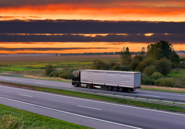 istock Trucks with Semi-trailer driving on highway on sunset background 1310793451