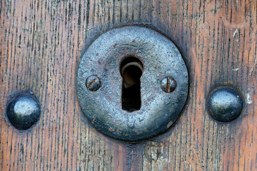 Close up of an old forged metal keyhole on an old wooden door