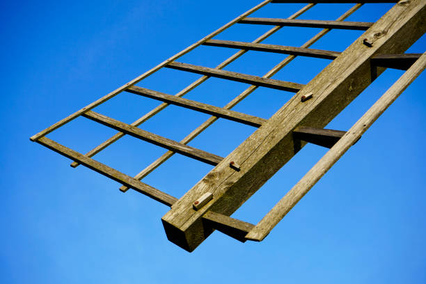 Wings of a windmill with a blue sky in the background. Wooden structure.