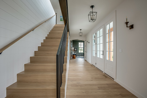 Natural wood flooring and stairs with black railing and white walls