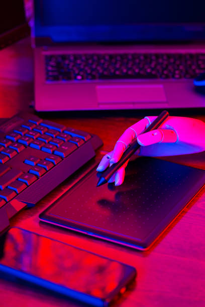 istock Digital design concept with a robot. Creative designer workplace in neon light. Digital tablet for drawing and an artificial arm with a pen. Distant work 1310801398