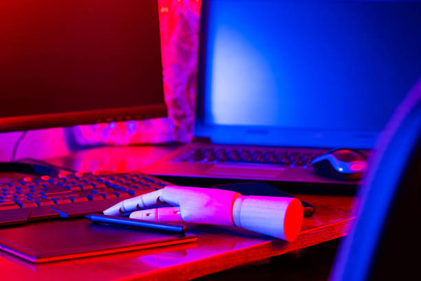 istock Digital design concept with a robot. Creative designer workplace in neon light. Digital tablet for drawing and an artificial arm with a pen. Distant work 1310801419