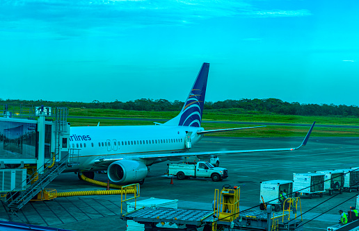 Panama City International Airport, Panama - 08 February, 2015: A Copa Airlines Boeing 737-700 is being prepare for its next departure by an airbridge at Panama City Airport. In the background is the actual airport runway. Some air cargo containers are seen to the right.