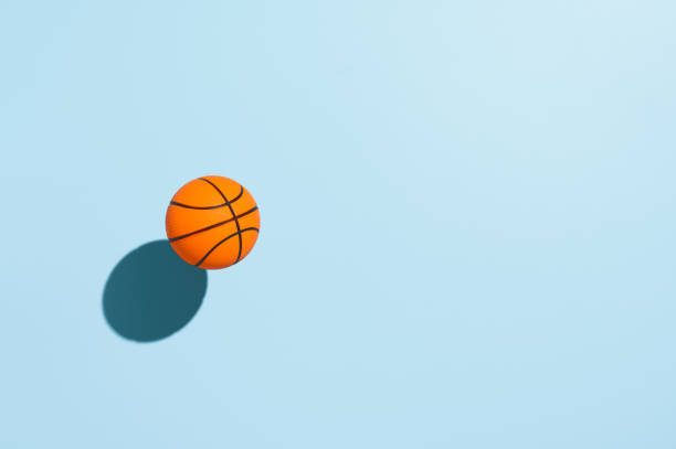 istock Orange basketball ball, hovering over pastel blue background. Minimal image with copy space, top view 1310802532