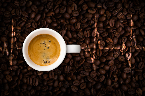 Coffee cup and cardiogram on coffee beans background. View top