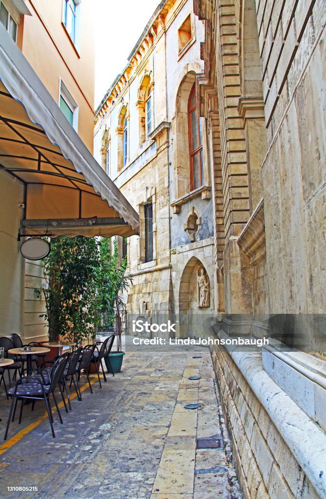 Alley with Cafe and Sagredo Fountain in Heraklion, Greece An alley with cafe and the Sagredo Fountain, Built by Giovanni Sagredo between 1602-1604, which is in the northwest corner of today's Loggia building in Heraklion, Crete, Greece. Alley Stock Photo