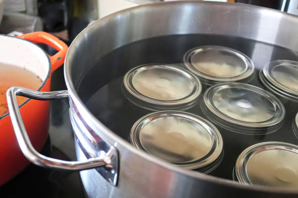 beizengläser in einem topf voller wasser - jar canning food preserves stock-fotos und bilder
