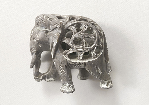 gray figurine of an elephant trumpets held high up on the side