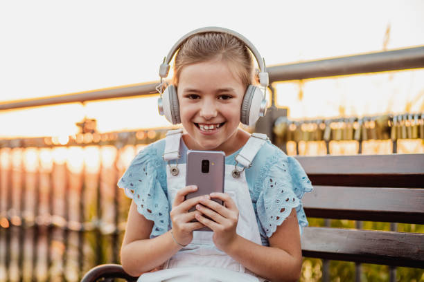 istock Little girl is using mobile phone on the bench 1310810788
