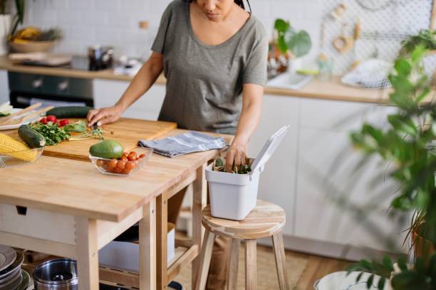 Woman putting organic waste in compost bin African woman preparing healthy vegetarian food. Cutting vegetables into small pieces. Summer chopped veggie salad compost stock pictures, royalty-free photos & images