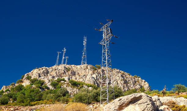 istock Antennas at rocky mountain peak, sunlight, blue sky, green trees 1310811759