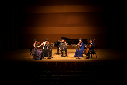 Five musicians playing violin, viola, and cello at classical music concert