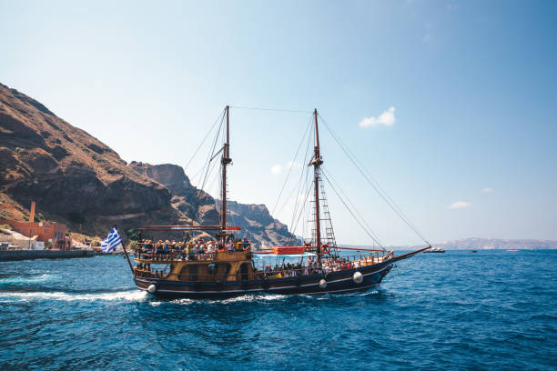 Santorini, Greece - June 10, 2019: Tourists ship full of tourists sailing out of the Old Port of Fira. Ship going towards Palea Kameni and Nea Kameni, small uninhabited volcanic islands at the center of the Santorini Caldera. It is a popular spot for waterside trips.