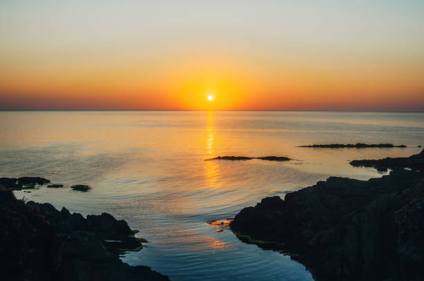 Beautiful sunrise over the sea near a rocky sea coast.